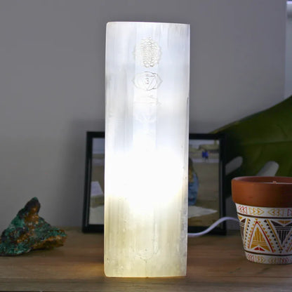 Lampe en sélénite gravée allumée, diffusant une lumière douce pour la relaxation et la méditation